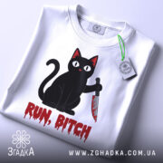 Футболка кіт маніяк, біла, складена на поверхні, фон світлий, принт чорного кота з ножем і написом 'RUN, BITCH' червоним кольором, на футболці є етикетка.