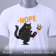 Футболка кіт мем, біла, зображена з верхнього ракурсу, фон світлий, принт з чорним котом, що піднімає лапу, з написом '-NOPE' жовтого кольору, на футболці є етикетка з зеленим шнурком.