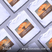 Футболка кіт не треба кричати, біла футболка з принтом, зображення кота на фоні вибуху, текст на українській мові, ракурс спереду, фон світлий.