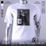 Футболка кіт патріот, біла, зображена на манекені, фон світло-сірий, принт з котом, що тримає пляшку вина з гербом України, котяче обличчя з усмішкою.