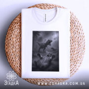 Футболка кіт проти динозавр, біла, складена на плетеній кошику, фон білий, принт з котом, що лякається динозаврів, на фоні тропічний ліс.