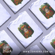 Футболка кіт у квітах, біла, зображена з фронтального ракурсу на манекені, фон світло-сірий, принт з котом у квітковому вінку та птахами, яскраві кольори квітів і зелені.