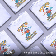 Футболка клуб емоційних гойдалок, біла, зображена з правого ракурсу, на фоні світло-сірого кольору, принт з веселим хлопчиком на гойдалці під парасолькою, текст "КЛУБ ЕМОЦІЙНИХ ГОЙДАЛОК" в жовтому та блакитному кольорах.