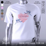 Футболка кохай птахи, біла, зображена з правого боку, на фоні світло-сірого кольору, принт з двома журавлями, що летять, на рожевому серці з написом 'Кохай'.