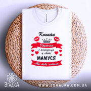 Футболка кохана дружина, біла, зображена зверху на плетеному кошику, фон білий, принт червоний з чорним текстом і сердечками, напис "Кохана Дружина і найкраща у світі МАМУСЯ Ми тебе любимо".