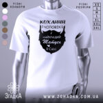 Футболка коханий чоловік, біла, зображена з фронтального ракурсу на манекені, фон світло-сірий, принт чорного кольору з написом 'Коханий чоловік і найкращий татусь в світі'.