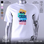 Футболка кольорові касети, біла, зображена з фронтального ракурсу на манекені, фон нейтральний, принт складається з кольорових касет з написом 'REAL MUSIC LOVER' у темно-синьому кольорі.