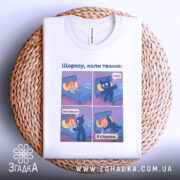 Футболка коли темно, біла, зображена на плетеній основі, фон натуральний, принт той же, з чотирма коміксами, що демонструють розмову між хлопчиком і синім персонажем.