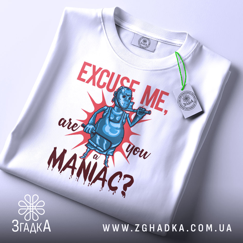Футболка комічний маніяк, біла, складена на поверхні, фон світло-сірий, принт з персонажем у масці, що тримає трубку, текст червоним кольором, з етикеткою на рукаві.