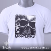 Футболка король мертвих, біла, складена на поверхні, з видимим етикеткою, фон світло-сірий, принт з черепом та текстом 'король мертвих' у чорному кольорі.
