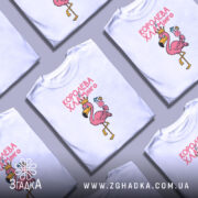 Футболка королева хламінго, біла, зображена з правого ракурсу, на фоні світло-сірого кольору, принт з рожевим фламінго в короні, що тримає коктейль. Текст на футболці виконаний у рожевому кольорі.