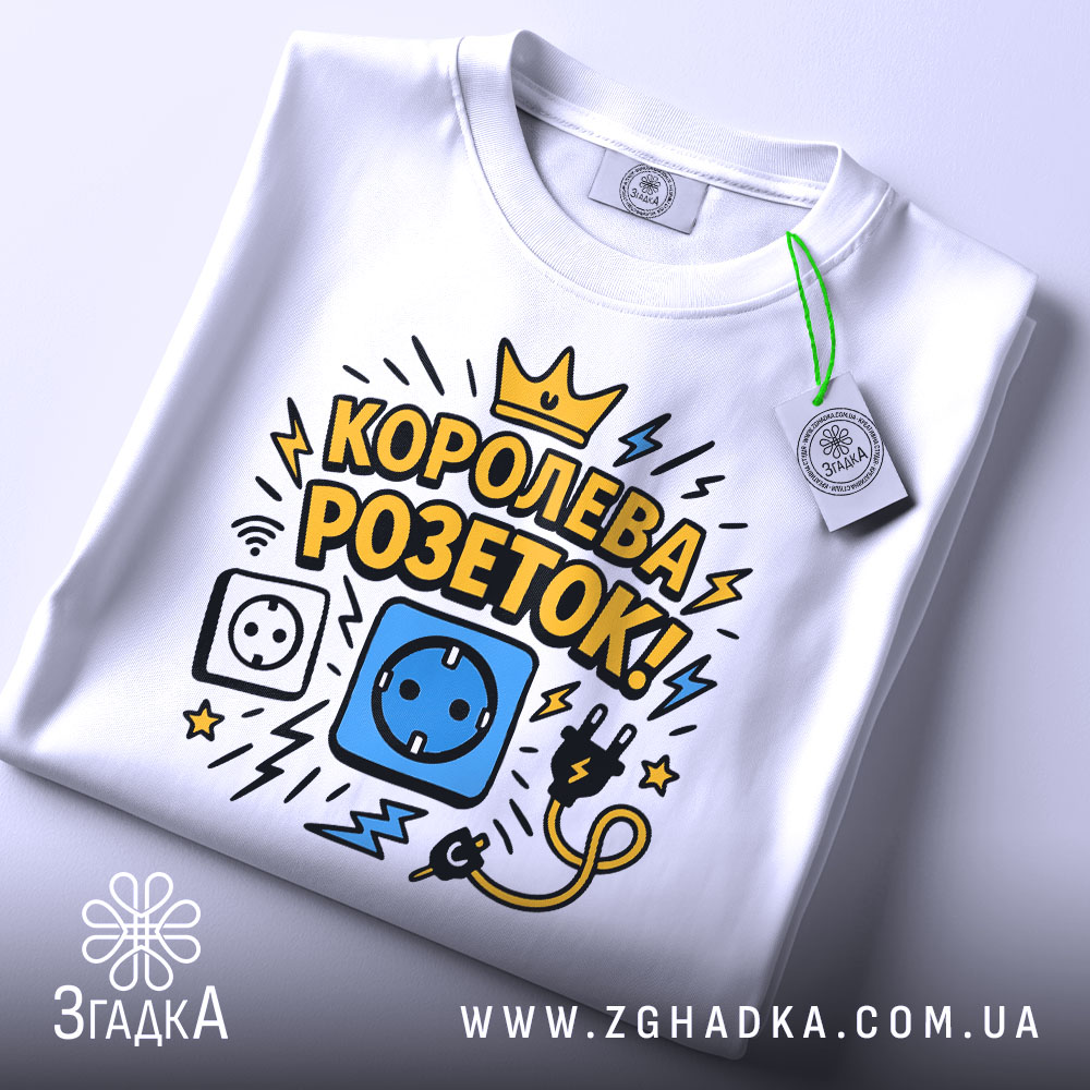 Футболка королева розеток білого кольору, зображена зверху, на фоні світло-сірого кольору, принт з малюнками розетки, електричного шнура та блискавок, текст "КОРОЛЕВА РОЗЕТОК!" у жовтому та чорному кольорах, на футболці є етикетка.