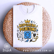 Футболка королева розеток білого кольору, зображена зверху на плетеній основі, фон світло-сірий, принт містить малюнки розетки, електричного шнура та блискавок, текст "КОРОЛЕВА РОЗЕТОК!" у жовтому та чорному кольорах.