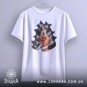 Футболка котяча любов, біла, підвішена на вішалці, фон світлий, принт зображає руку з манікюром, що тримає кілька чорних котів, коти з виразами радості.