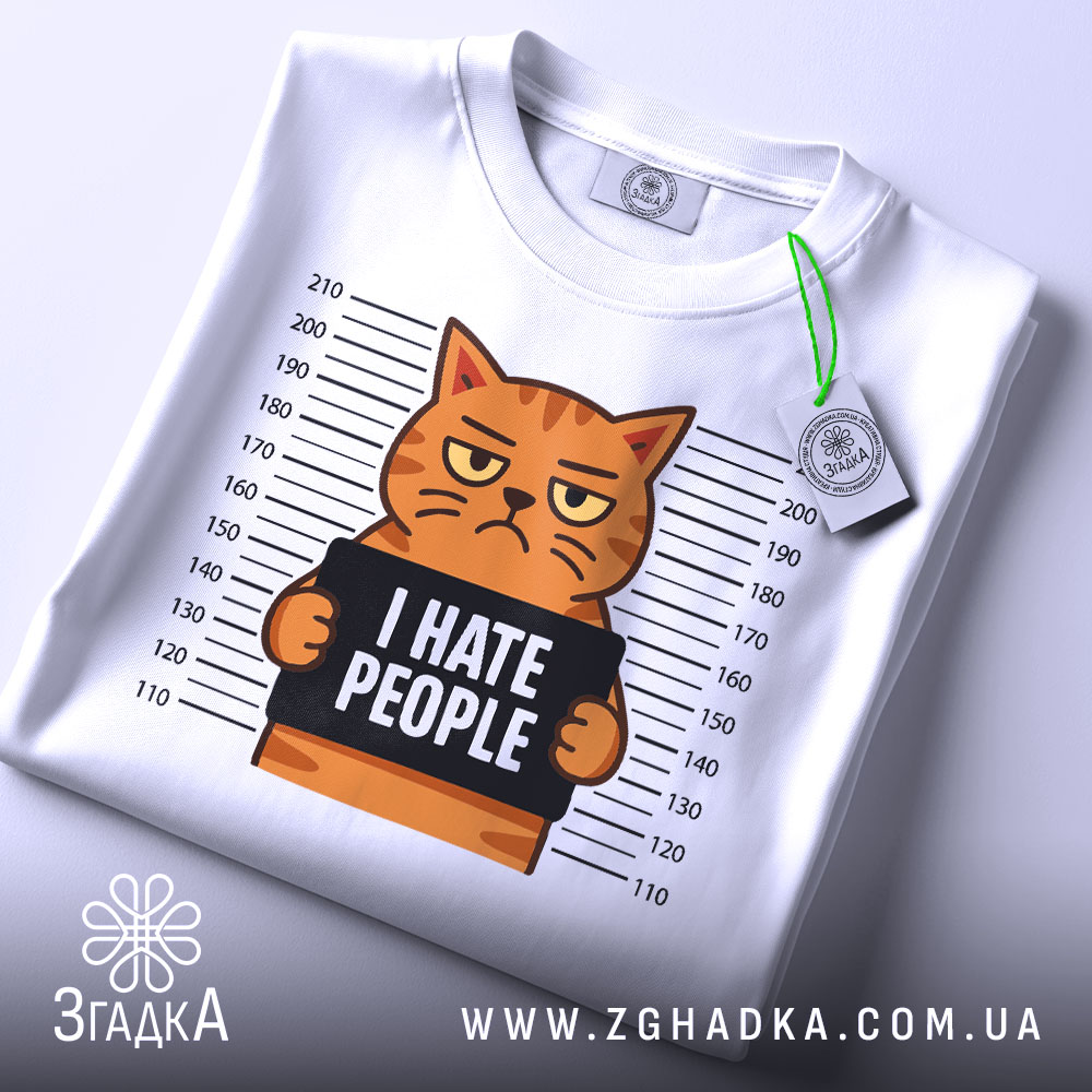 Футболка котячий гумор хейт, складена біла футболка з принтом кота, що тримає табличку з написом 'I HATE PEOPLE', фон світло-сірий, видно етикетку з логотипом, принт чіткий і кольоровий.