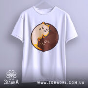 Футболка котячий інь-янь, біла, підвішена на вішалці, фон світло-сірий, принт з двома котами, один кремового кольору, інший коричневий, обидва з закритими очима, виглядають спокійно.