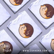 Футболка котячий інь-янь, біла, зображена на манекені з правого боку, фон світло-сірий, принт з двома котами, один кремового кольору, інший коричневий, обидва з закритими очима, виглядають спокійно.