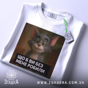Футболка котячий настрій, біла, зображена зверху, фон світло-сірий, принт з котом з усмішкою та текстом "ЩО Б ВИ БЕЗ МЕНЕ РОБИЛИ", на футболці підвішений етикет.