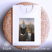 Футболка коти Київ, біла, складена на плетеній кошику, фон світлий, принт з двома котами на фоні київських церков.