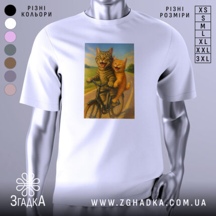 Футболка коти на велосипедi, біла, зображена з фронтального ракурсу, на фоні світло-сірого градієнту, принт з двома котами на велосипеді, один сірий, інший рудий, обидва з усмішками, на фоні зеленого пейзажу.