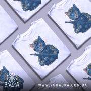Футболка котик герой, біла футболка з принтом кота в військовій формі, з автоматом у руках, фон світлий, деталі принта яскраві, котик має різнокольорові очі та військову кепку.