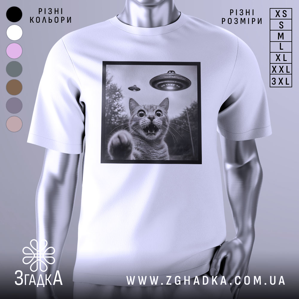 Футболка котик і НЛО, біла футболка на манекені, зображення кота з відкритим ротом і піднятою лапою, на фоні видно НЛО, принт в чорній рамці, фон світлий.