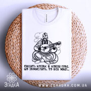 Футболка козак грає, біла футболка, складена на плетеній основі, принт козака з кобзою, фон світлий, деталі принта чіткі.