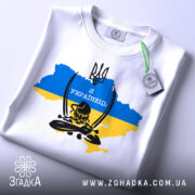 Футболка козак я українець, біла, складена на поверхні, фон світлий, принт з тризубом та написом 'Я УКРАЇНЕЦЬ' на фоні карти України в жовто-блакитних кольорах, з зеленим ярликом.