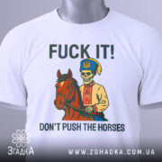 Футболка козак не жени. Біла футболка, складена на столі, з принтом, що зображує скелета в українському вбранні на коні. На фоні світло-сірий градієнт. Текст на футболці: 'FUCK IT! DON'T PUSH THE HORSES', з етикеткою на комірці.