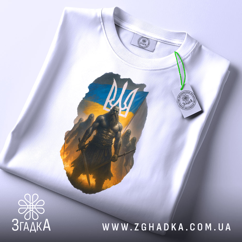 Футболка козак з тризубом, біла, зображена на столі, фон світло-сірий, принт з козаком на фоні українського прапора, з етикеткою на рукаві.