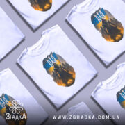 Футболка козак з тризубом, біла, зображена на манекені, фон світло-сірий, принт з козаком на фоні українського прапора та темних силуетів.