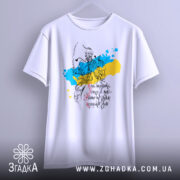 Футболка козацька воля, біла, підвішена на вішалці, фон світло-сірий, принт з козацьким воїном на фоні жовто-блакитних плям, текст українською мовою.