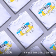 Футболка країна незламних, біла, зображена з правого ракурсу на манекені, фон нейтральний, принт з рукою, що тримає напис "Країна сильних!" на фоні карти України в жовто-блакитних кольорах.