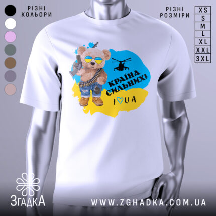 Футболка країна вільних, біла, зображена на манекені, фон світло-сірий, принт з ведмедиком у сонцезахисних окулярах, з автоматом і гелікоптером, текст "Країна сильних! I ♥ UA" у жовто-блакитному кольорі.