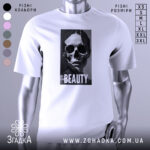 Футболка краса без ілюзій, білого кольору, зображена з фронтального ракурсу на манекені, фон світло-сірий, принт зображає череп та напис 'BEAUTY' на чорному фоні.