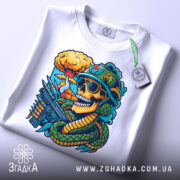 Футболка креатив бойовий, біла, зображена на столі, ракурс зверху, фон світло-сірий, принт з черепом у військовій касці, з окулярами, з автоматом і змією, на фоні ядерного вибуху, з етикеткою.