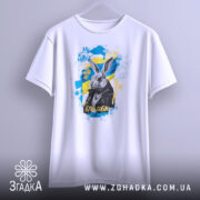 Футболка кролик будь собою. Біла футболка, підвішена на вішалці, з принтом кролика в чорній куртці на жовто-блакитному фоні. Текст "БУДЬ СОБОЮ" виділяється яскравими кольорами.