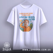 Футболка кругом якась фігня, біла футболка на вішалці, ракурс спереду, фон світло-сірий, принт з зображенням чоловіка з рудим волоссям, який прикриває очі від сонця, текст зверху оранжевого кольору, текст внизу блакитного кольору.