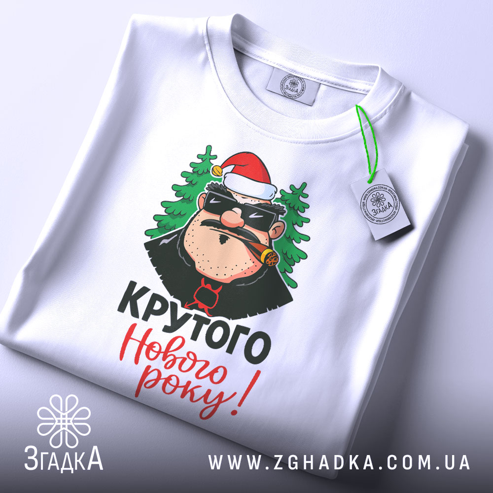 Футболка крутого Нового Року, біла, зображена зверху, фон світлий, принт з персонажем у червоній шапці та ялинками, текст 'Крутого Нового року!' яскравими кольорами, на футболці є етикетка.
