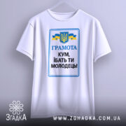 Футболка кум молодець. Біла футболка з коротким рукавом, зображена з фронтального ракурсу, на фоні світло-сірого градієнту. Принт містить текст 'ГРАМОТА КУМ, ІБАТЬ ТИ МОЛОДЕЦЬ!' у синьому та чорному кольорах, а також герб України та жовто-блакитні стрічки.