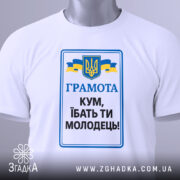 Футболка кум молодець. Біла футболка, зображена зверху, на фоні світло-сірого градієнту. Принт з текстом 'ГРАМОТА КУМ, ІБАТЬ ТИ МОЛОДЕЦЬ!' у синьому та чорному кольорах, герб України та жовто-блакитні стрічки. На футболці видно етикетку з зеленим шнурком.