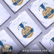 Футболка кум найкращий, біла, зображена з фронтального ракурсу на манекені, фон світло-сірий, принт з трофеєм та написом 'BEST КУМ' у жовтому та синьому кольорах.