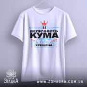 Футболка кума хрещена білого кольору, підвішена на вішалці, фон світло-сірий, принт з текстом "ВЕЛИЧНІСТЬ КУМА Найкраща в світі ХРЕЩЕНА" з червоною короною та блакитними елементами.