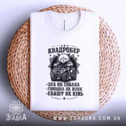 Футболка квадробер білого кольору, складена на плетеній основі, фон білий, принт чорного кольору з котом на квадроциклі та текстом.