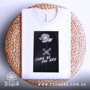 Футболка квітка монохром, біла, складена на плетеній кошику, фон світло-сірий, принт з чорним фоном, білою трояндою та написом 'COME AS YOU ARE'.