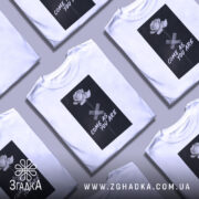 Футболка квітка монохром, біла, зображена на манекені, фон світло-сірий, принт з чорним фоном, білою трояндою та написом 'COME AS YOU ARE'.