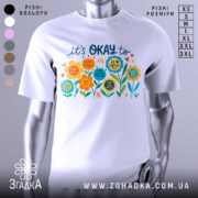 Футболка квіткова мотивація. Біла футболка з кольоровим принтом, зображеним на грудях, на манекені з металевим блиском. Принт містить різнокольорові квіти та текст, що закликає до позитивного мислення. Фон світло-сірий, що підкреслює яскравість кольорів принта.