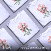 Футболка квіткові арт дні, біла, зображена з фронтального ракурсу на манекені, фон світло-сірий, принт з трьома червоними квітами та написом 'STRANGE DAYS' зеленого кольору.