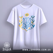 Футболка квітковий тризуб, біла, підвішена на вішалці, фон світло-сірий, принт у вигляді тризуба з квітковими елементами в жовтих, блакитних та зелених відтінках.