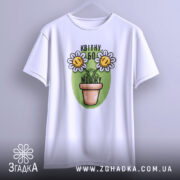 Футболка квітну бо можу, білого кольору, підвішена на вішалці, фон світло-сірий, принт з двома усміхненими соняшниками в горщику на зеленому фоні.